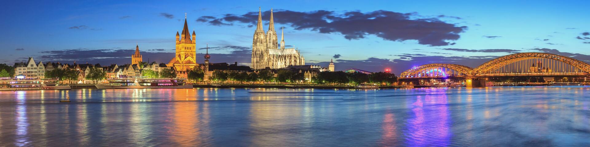 A city skyline with a prominent cathedral and a bridge reflecting on the water.