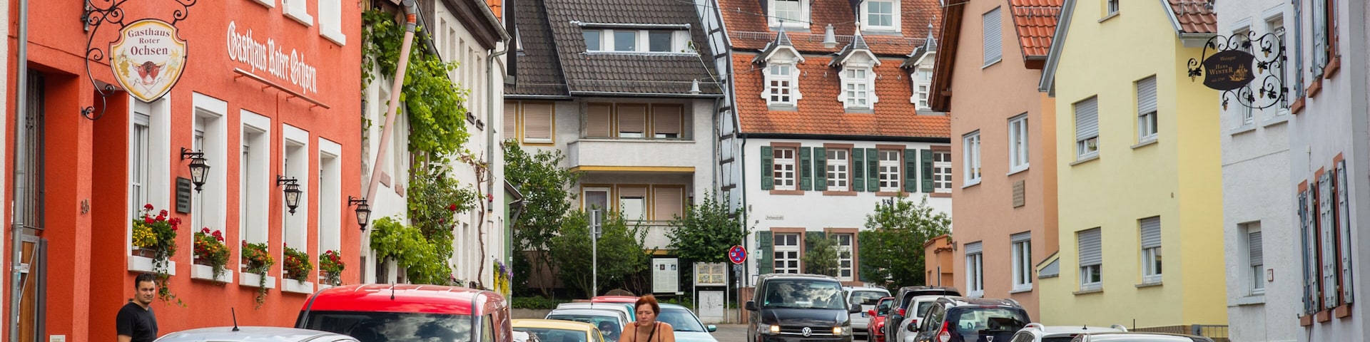 Eine enge Straße, gesäumt von bunten Gebäuden und parkenden Autos.