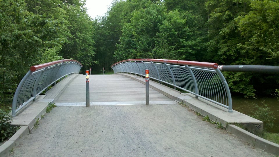 Hakenbrücke über die Pleiße unmittelbar im Nordnordwesten des Wildparks Leipzig im Mai 2015. Der Pleißeradweg bog links, vor Querung der Brücke, ab und verlief rechtsufrig der Pleiße weiter Richtung Süden. OSM-Karten Link.