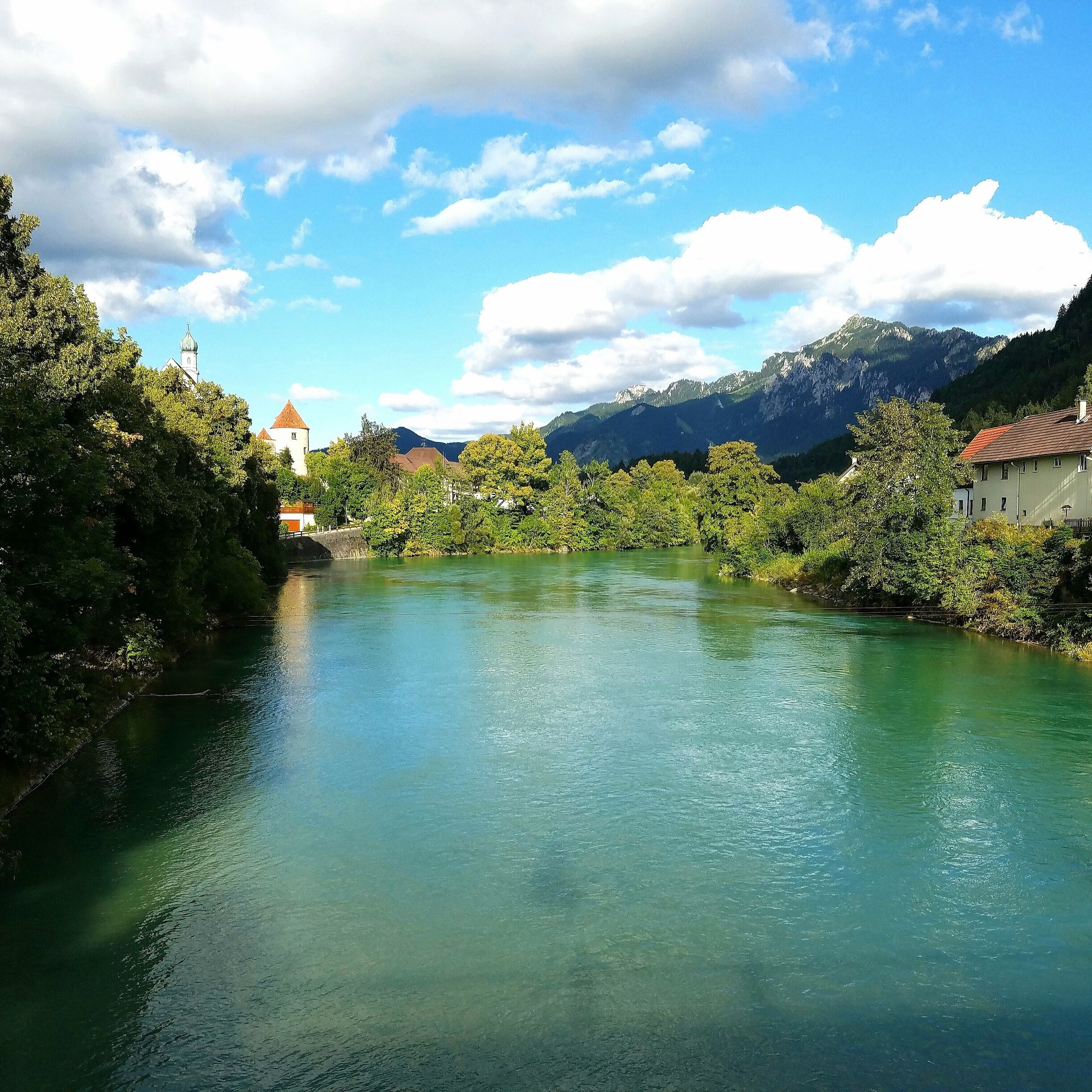 A river with a church and mountains in the background.