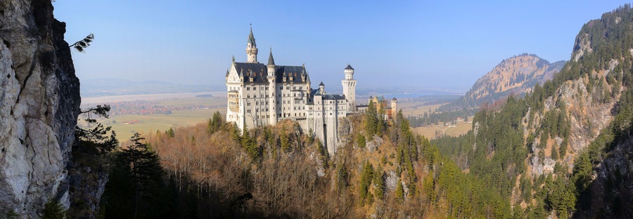 Eine Burg auf einem Hügel mit bewaldeter Bergkulisse.