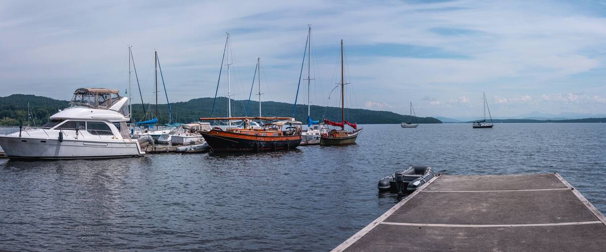 Lake Champlain summer landscape with moored boats, yachts, and walking dock in New York