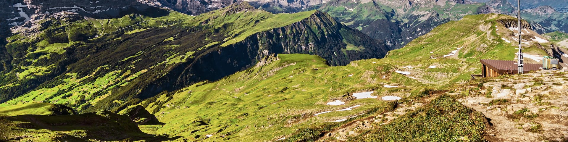 A mountainous landscape with a Swiss flag, snow-capped peaks, and green valleys.