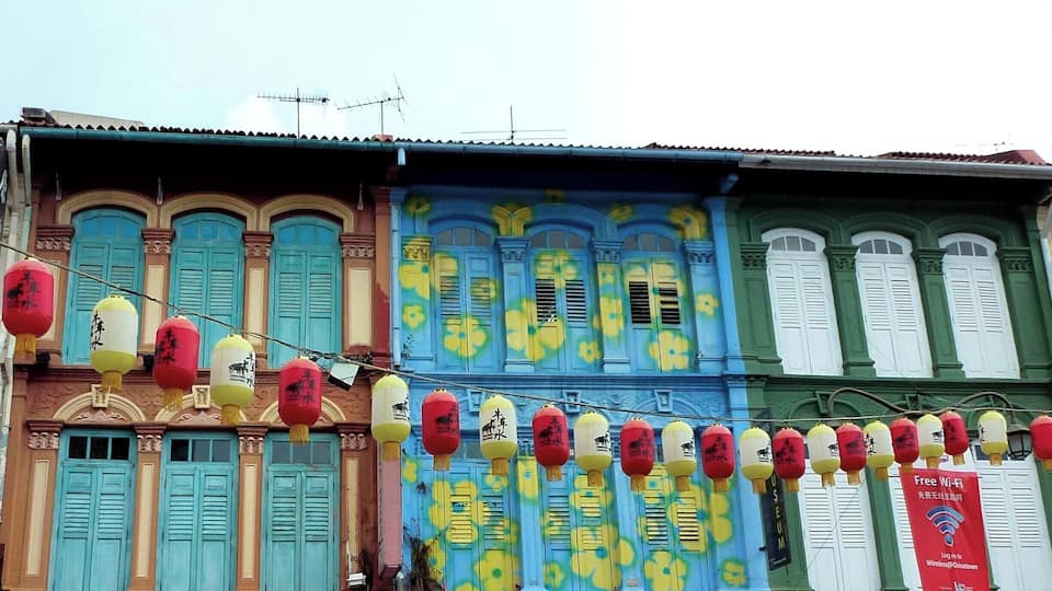 Colorful buildings with blue and green facades, traditional windows, and red lanterns.