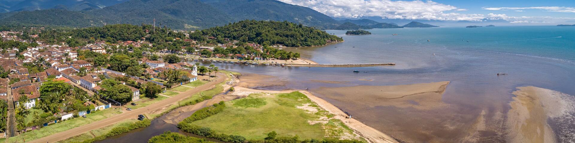 Panoramic aerial view to historic town Paraty, tidal river and Jabaquara with green mountains in background on a sunny day, Brazil, Unesco World Heritage