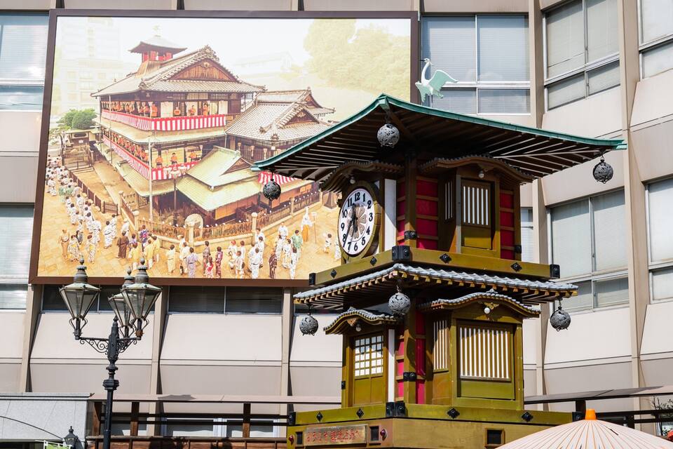 A traditional Japanese building with a clock and a mural of a temple.