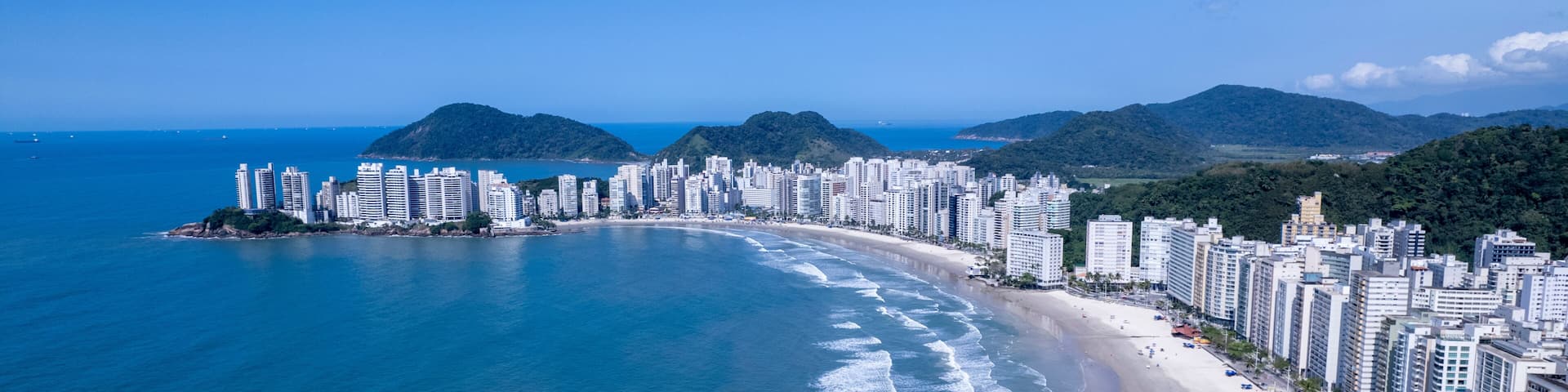 Aerial view of Praia da Pitangueiras beach in Guaruja, Sao Paulo showcasing glistening waters and high-rise buildings on a sunny day