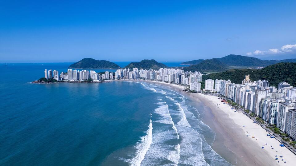 Aerial view of Praia da Pitangueiras beach in Guaruja, Sao Paulo showcasing glistening waters and high-rise buildings on a sunny day