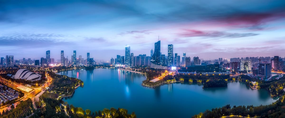 Une vue sur les gratte-ciel d’une ville au crépuscule, avec une vaste étendue d’eau au premier plan.