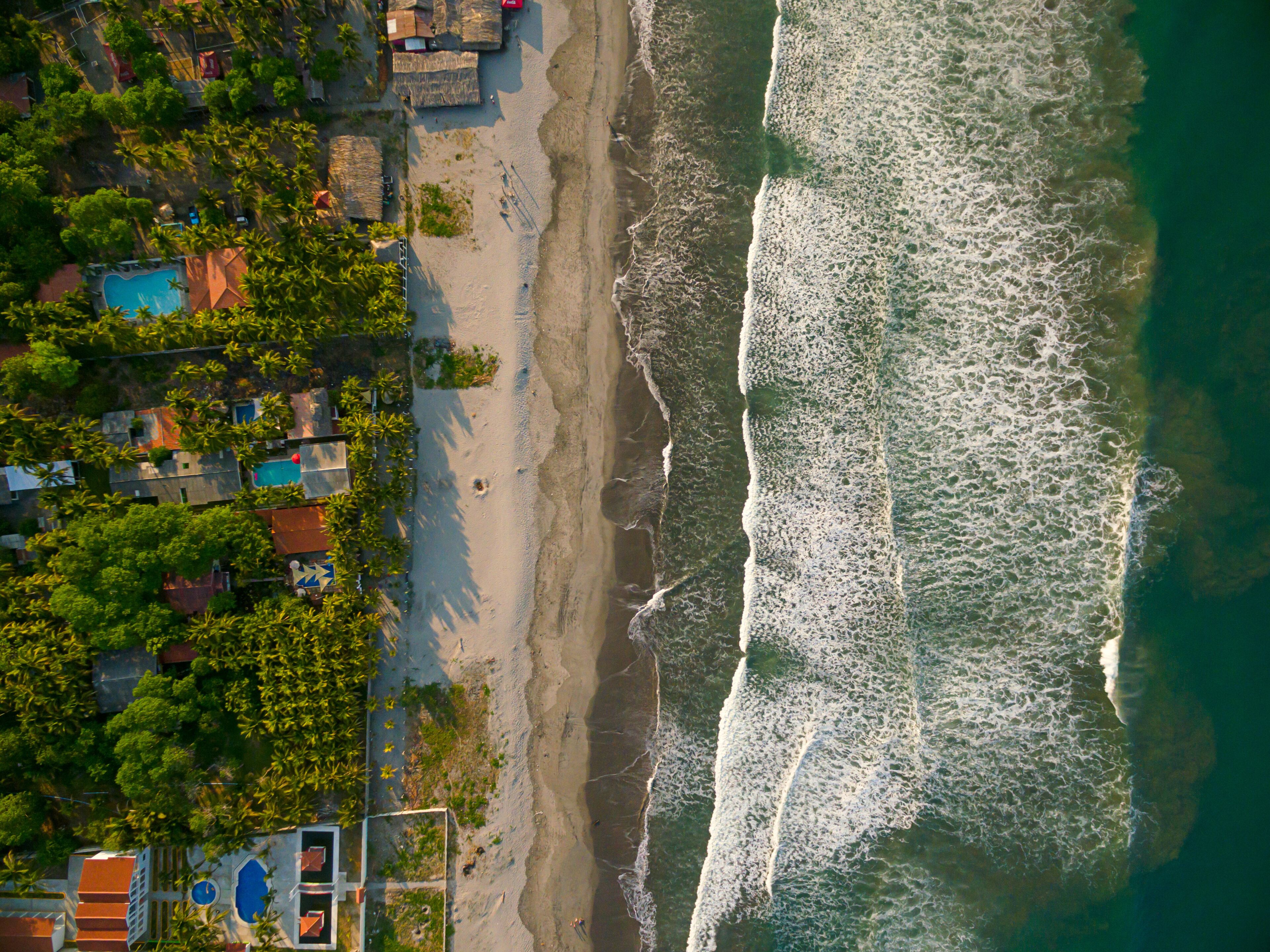 Una playa con olas, una piscina y casas.