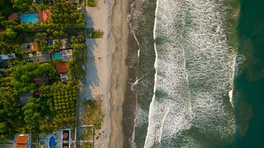 Une plage avec des vagues, une piscine et des maisons.