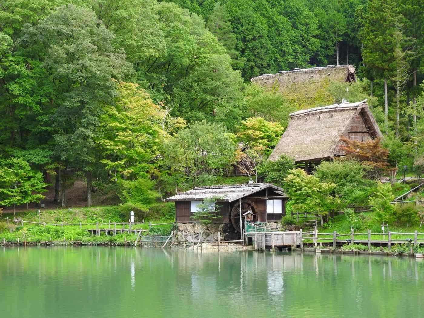 A traditional Japanese structure by a calm lake surrounded by lush greenery.