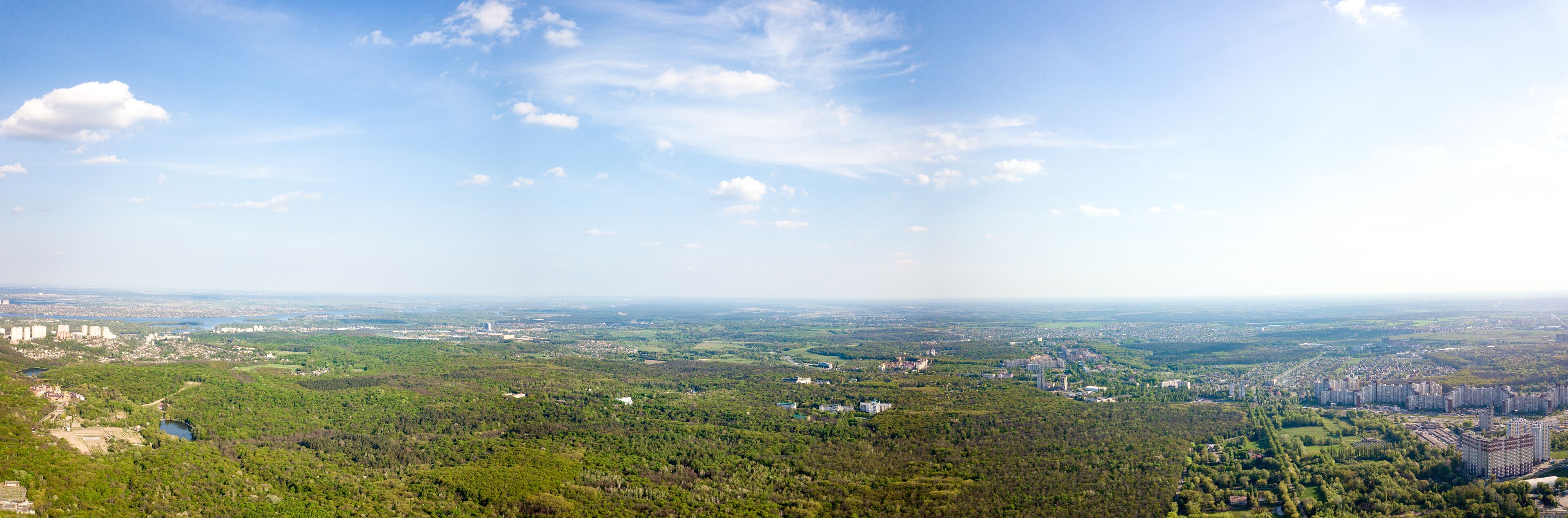 The panoramic bird's eye view shooting from drone to Holosiivskyi district with recreational area and urban infrastructure in Kiev, Ukraine at summer sunset.