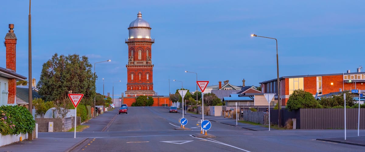 A street with a red brick tower, street signs, and houses.
