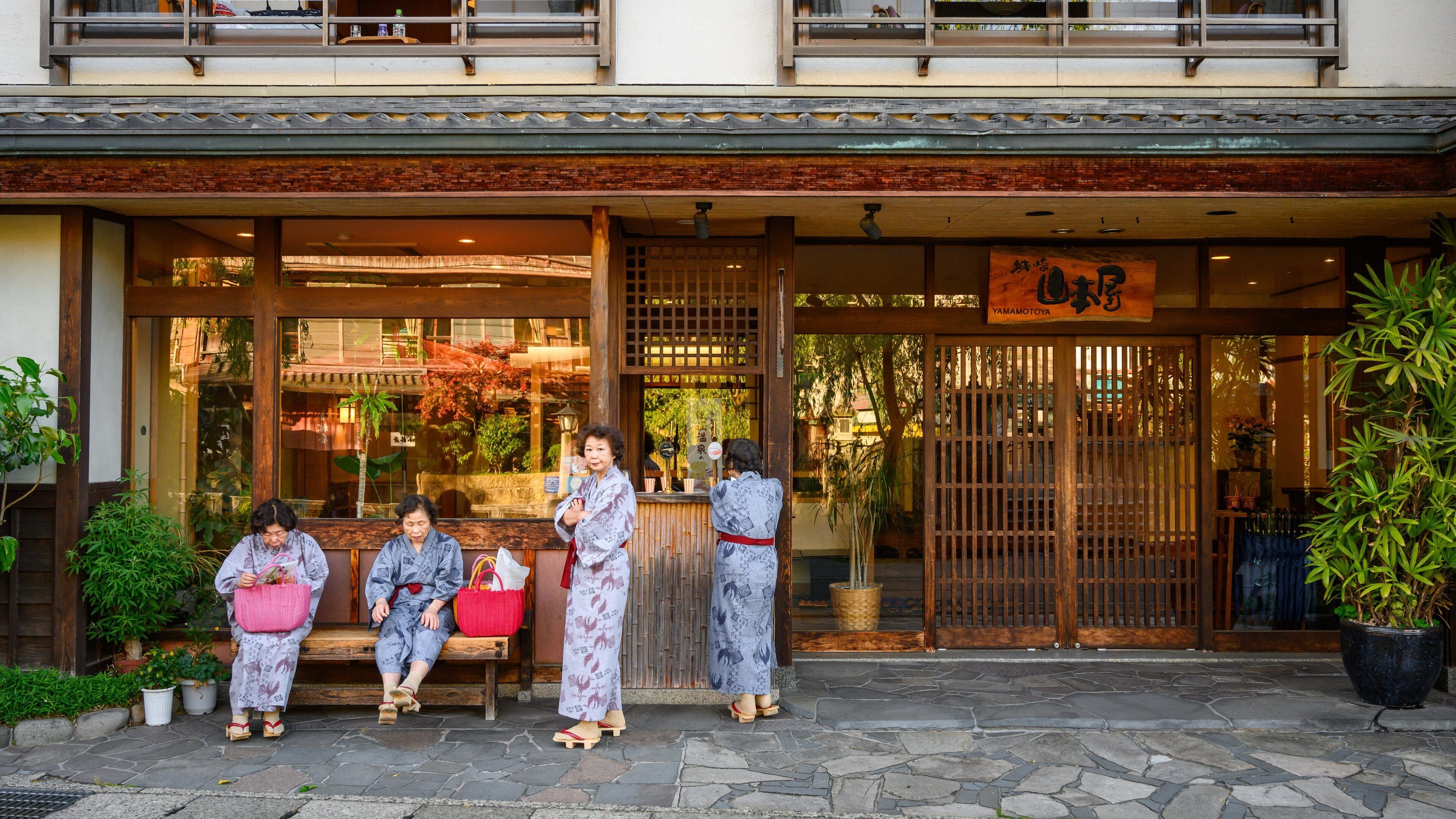 Edificio japonés tradicional con entrada de madera, un letrero y suelo de piedra.