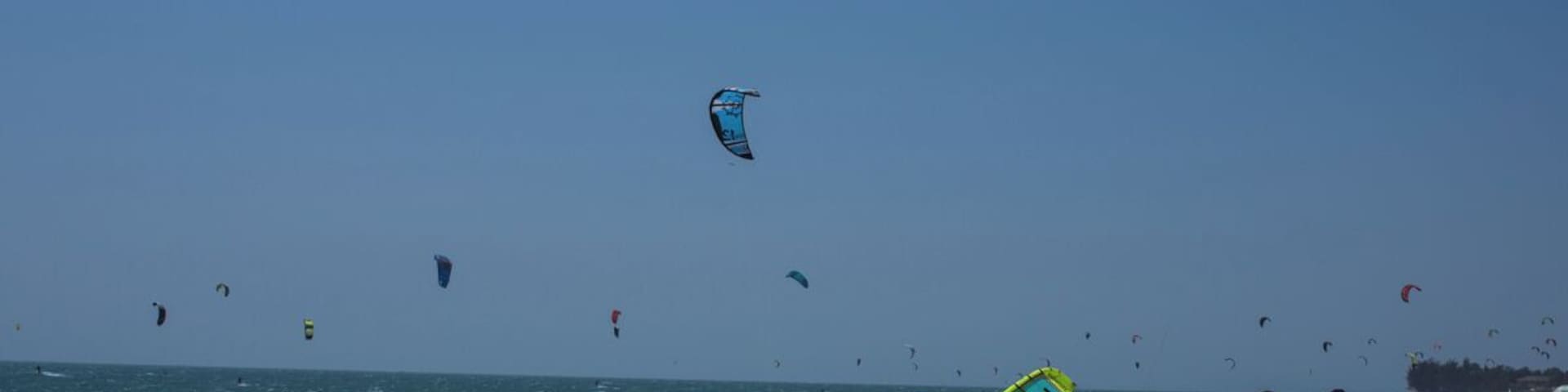 Una playa con gente y cometas volando.