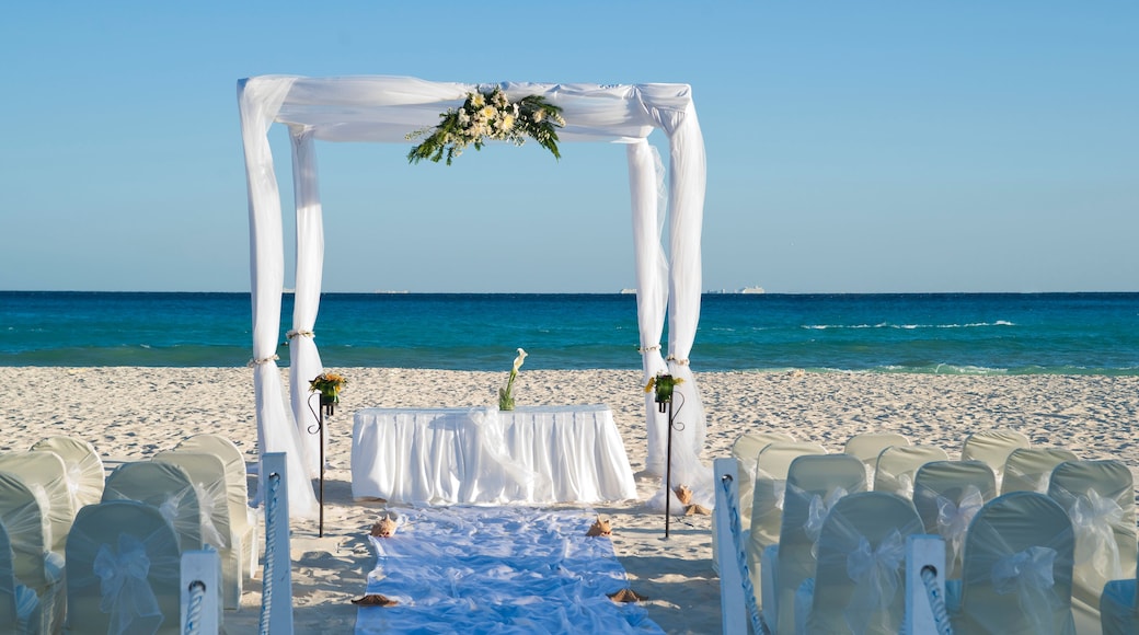 Decoración para una boda en la playa, con un arco blanco, pasillo y sillas.