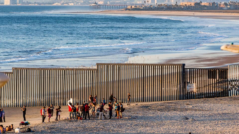 Mexican band plays for revellers in front of the border fence between Mexico and USA, room for text