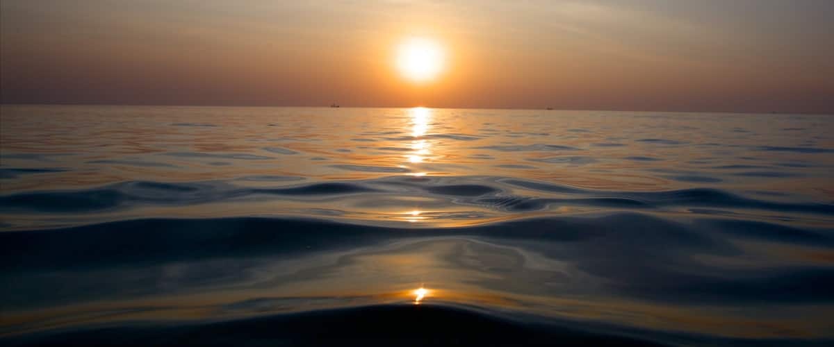 A sunset over a calm sea with gentle waves.