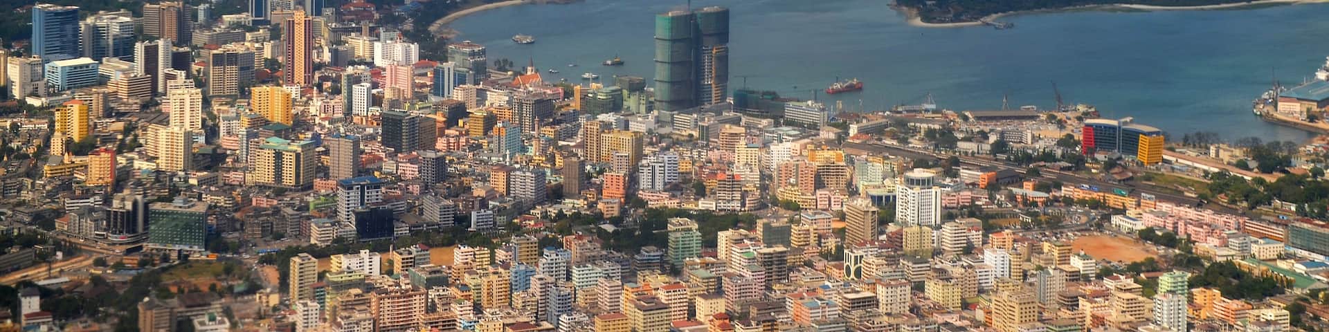 A coastal cityscape with dense urban development, a large body of water, and a distant island.