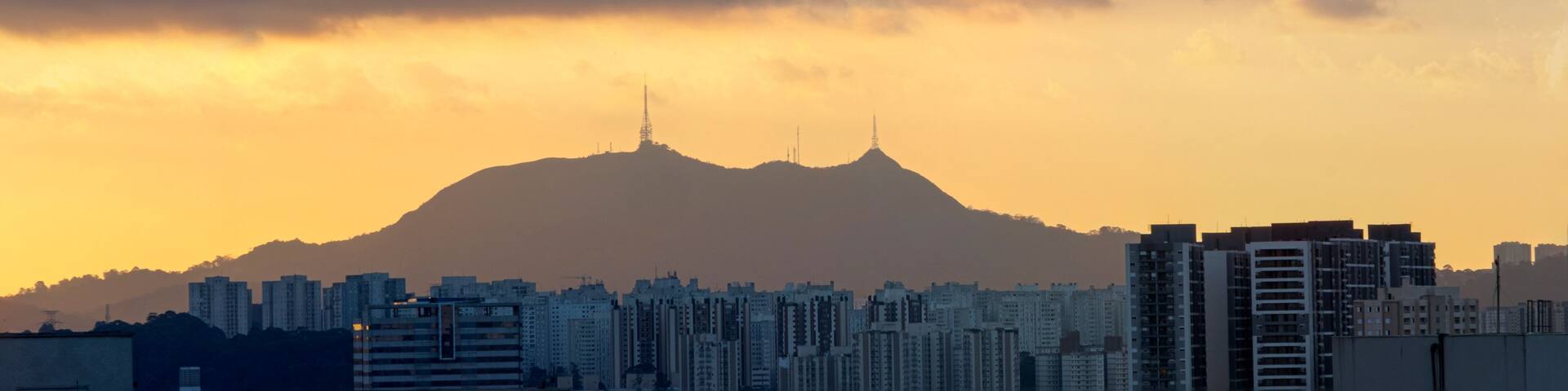 A cityscape with a mountain in the background during sunset.