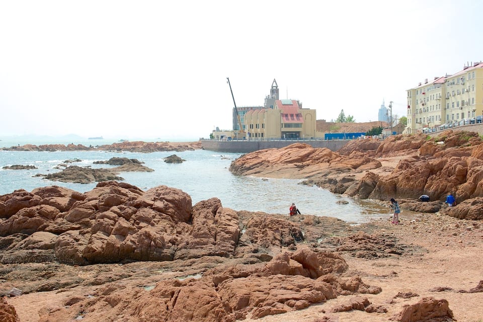 A rocky shoreline with buildings in the background.