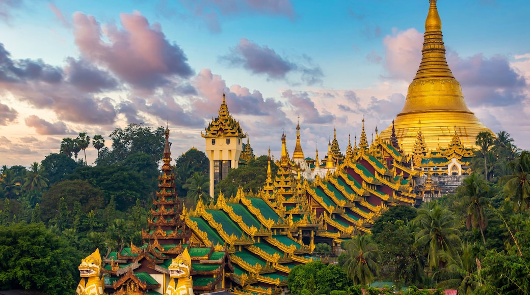 A golden pagoda surrounded by lush greenery and traditional architecture.
