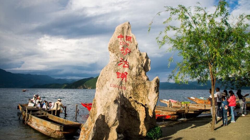 Ein großer Felsen mit chinesischen Schriftzeichen und ein See mit Booten.
