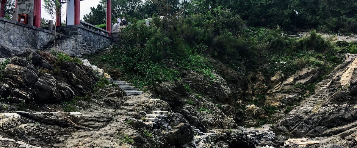 Looking up from the rocky coast at the small pagoda by the sea.