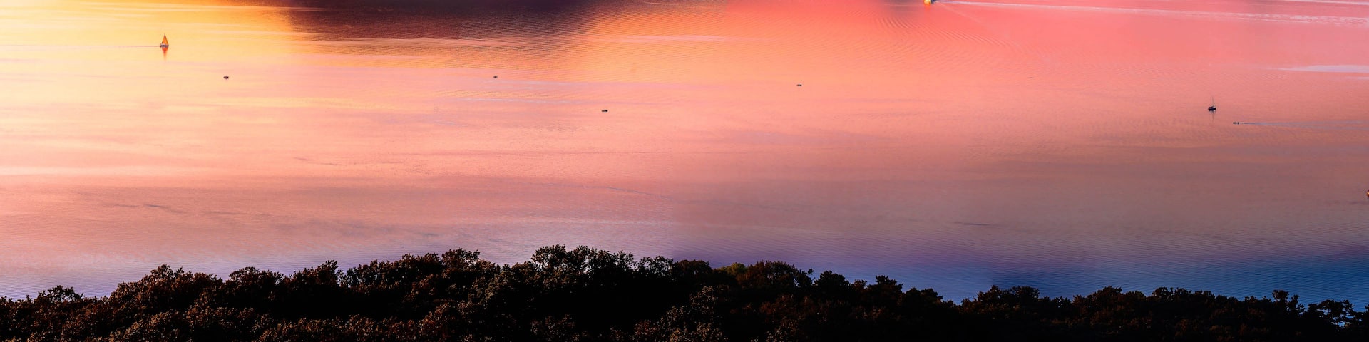 A calm lake with mountains in the background during sunset.