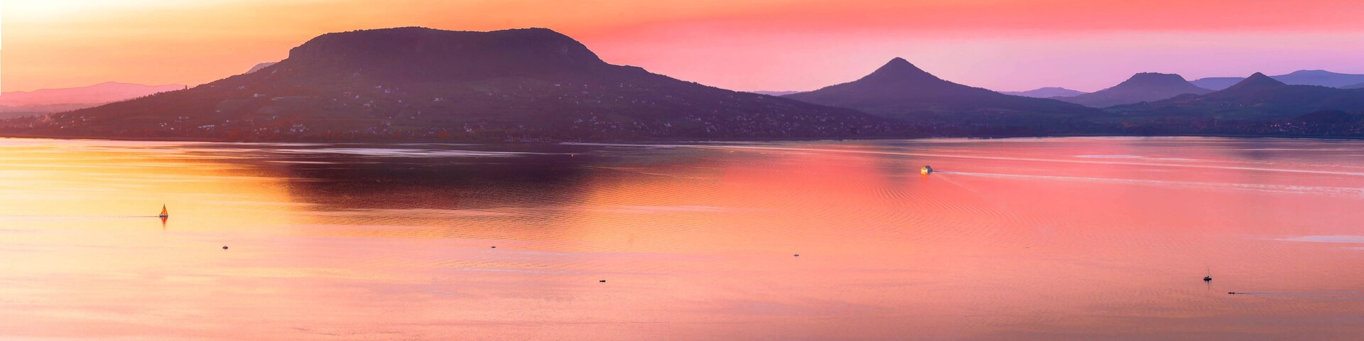 Um lago calmo com montanhas ao fundo durante o pôr do sol.