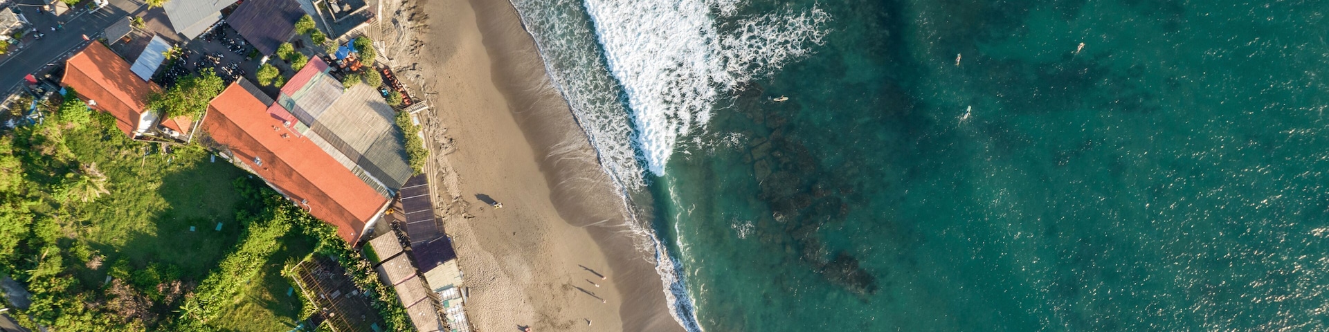Drone aerial view of beach and buildings on the shoreline at Batu Bolong; Canggu, Bali, Indonesia