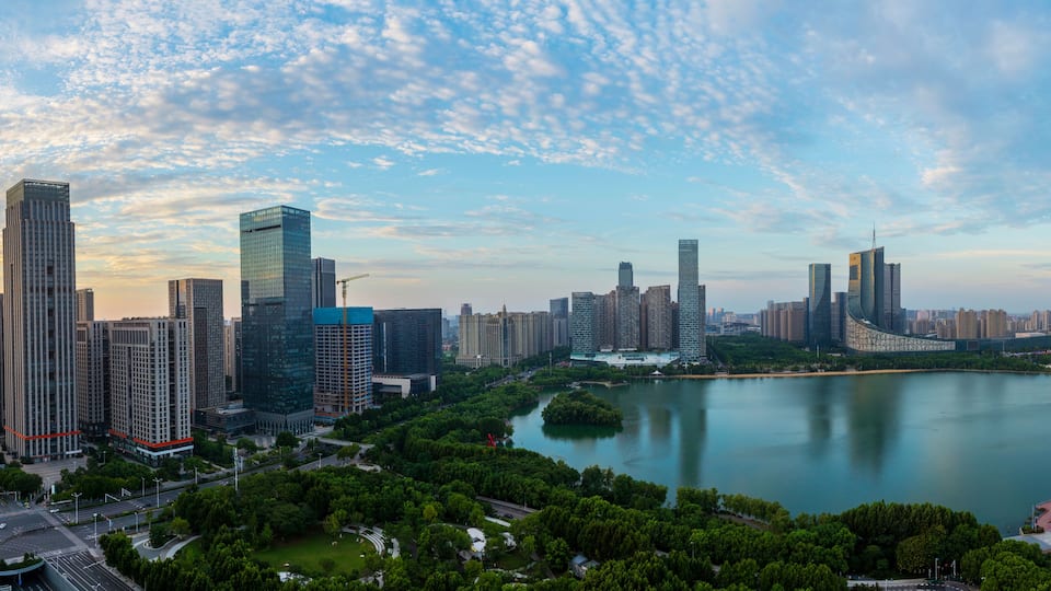 A cityscape with modern skyscrapers, a river, and surrounding greenery.