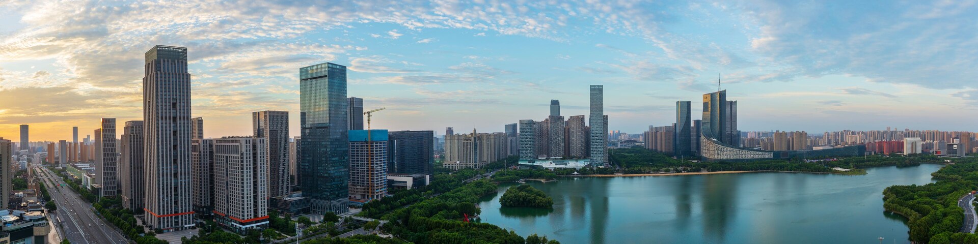 Paisagem urbana com arranha-céus modernos, um rio e áreas verdes ao redor.