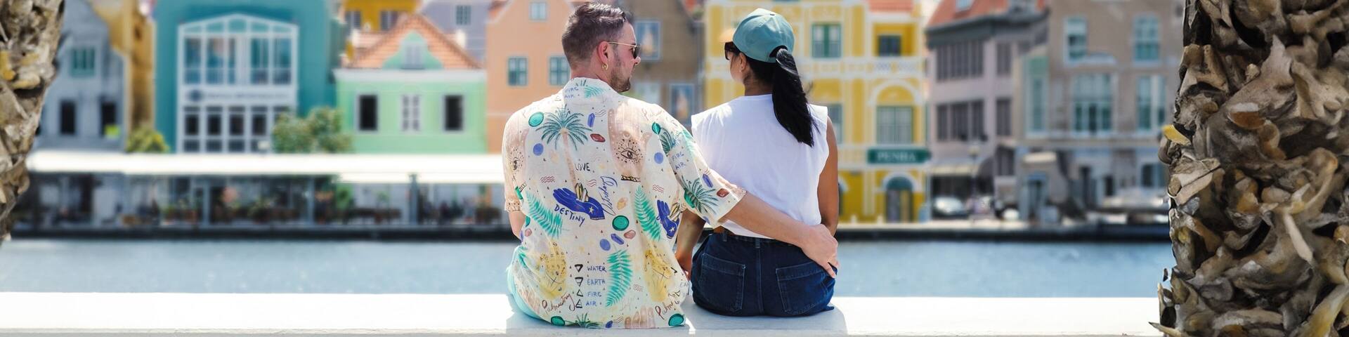 Willemstad Curacao has colorful buildings around Willemstad Punda and Otrobanda, multicolored homes on Curacao Caribean Island, couple of caucasian men and Asian women on vacation in Curacao.