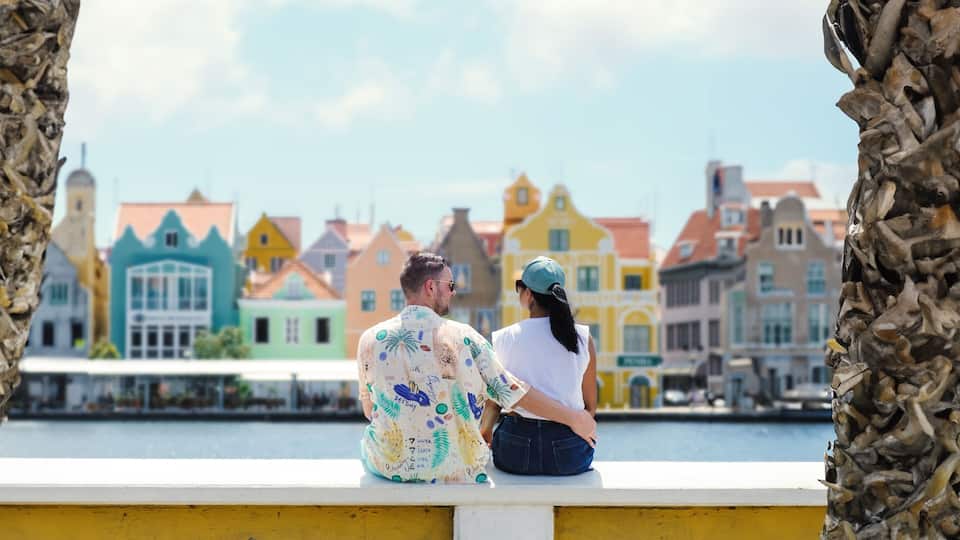 Willemstad Curacao has colorful buildings around Willemstad Punda and Otrobanda, multicolored homes on Curacao Caribean Island, couple of caucasian men and Asian women on vacation in Curacao.