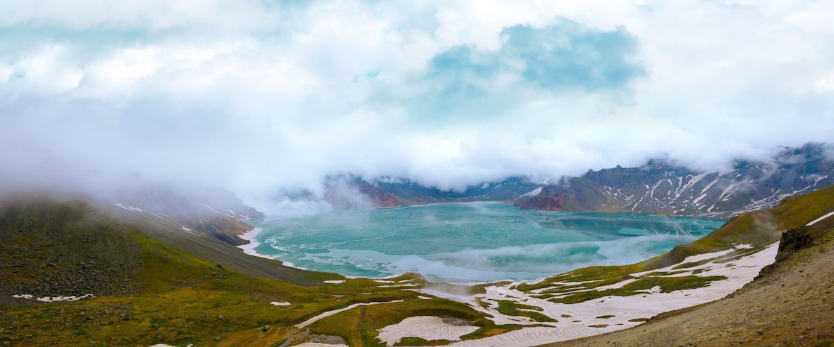 A glacial lake surrounded by mountains and snow patches.