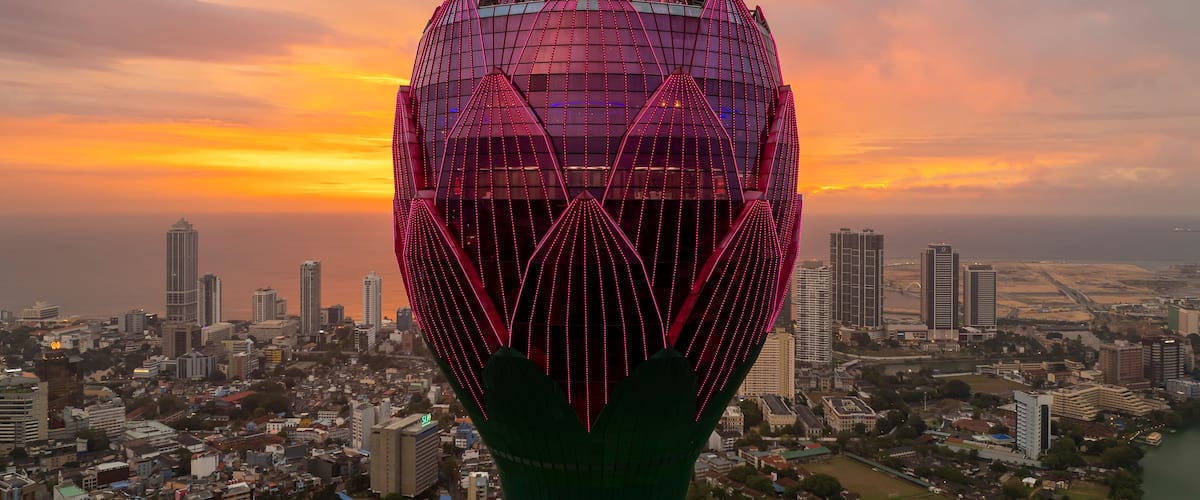 A cityscape with a prominent tower featuring a lotus-like design and pink lighting.