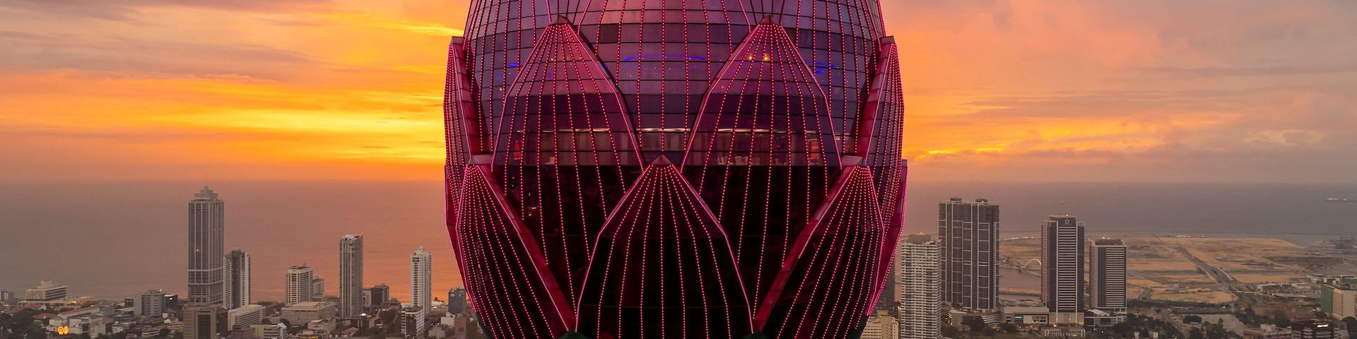 Paisagem urbana com uma torre imponente, design semelhante a uma flor de lótus e iluminação rosa.