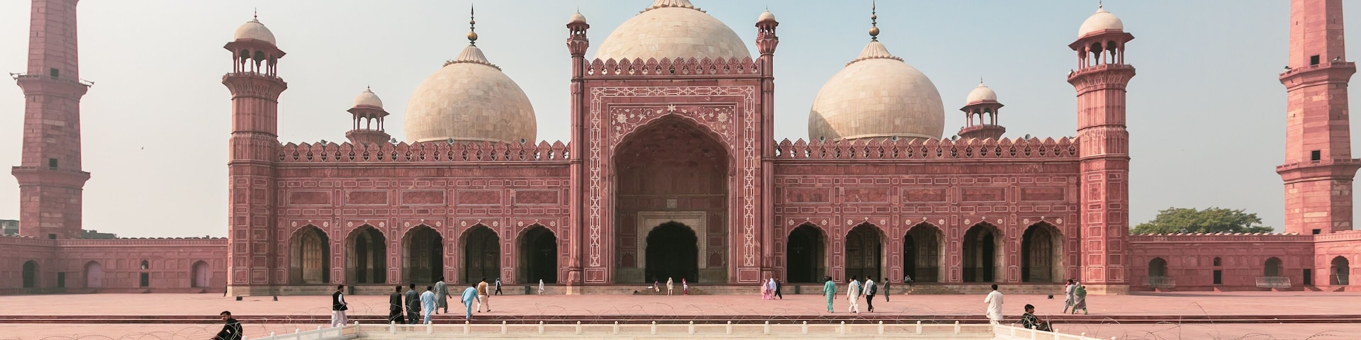 A large, pink, domed building with multiple minarets and arched doorways.