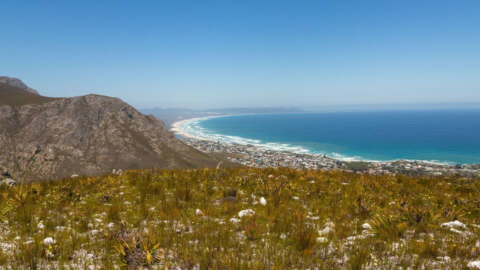 A coastal landscape with a mountain, beach, and ocean.
