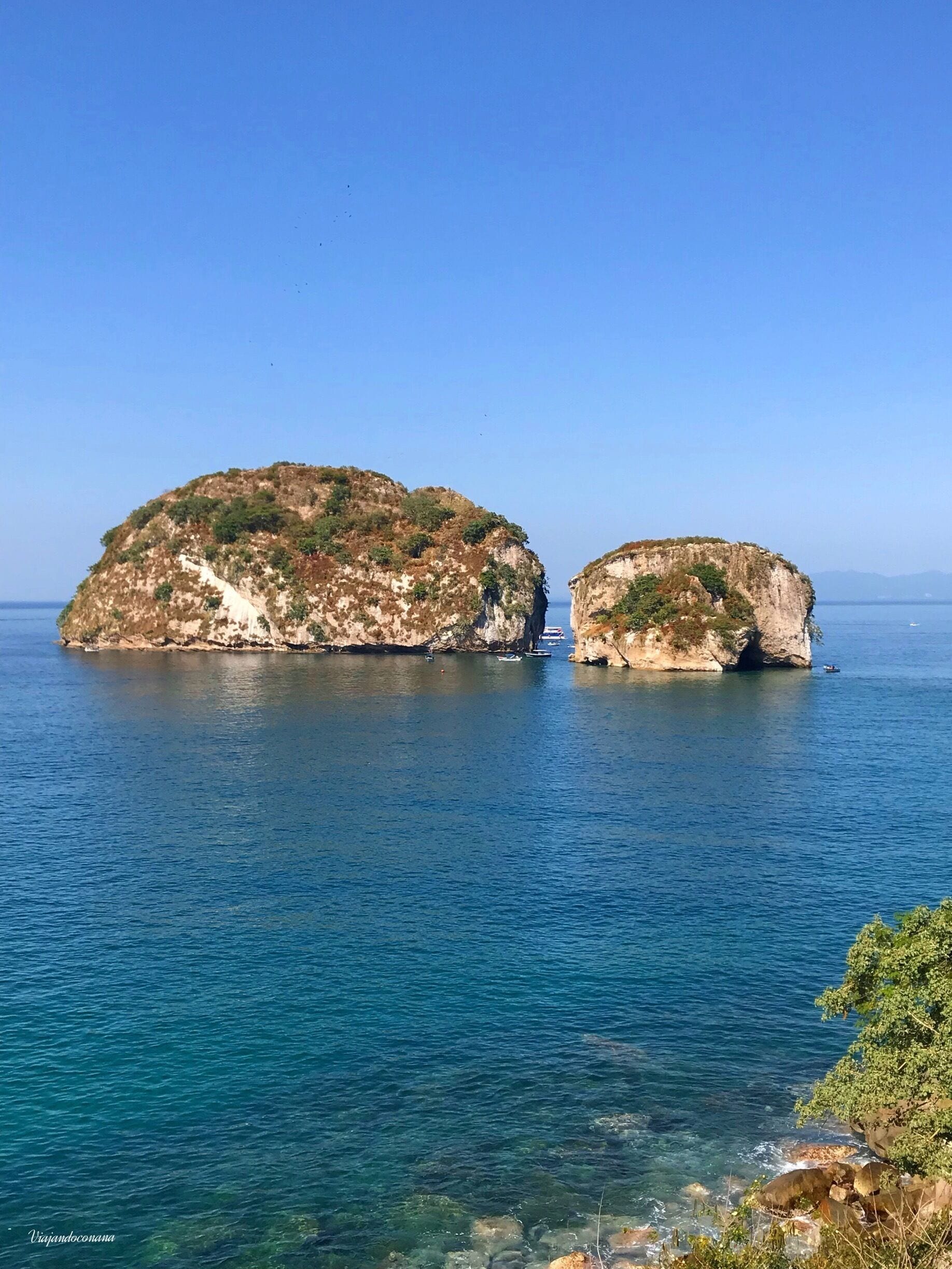 A coastal scene with two prominent rocky islands surrounded by clear blue waters.