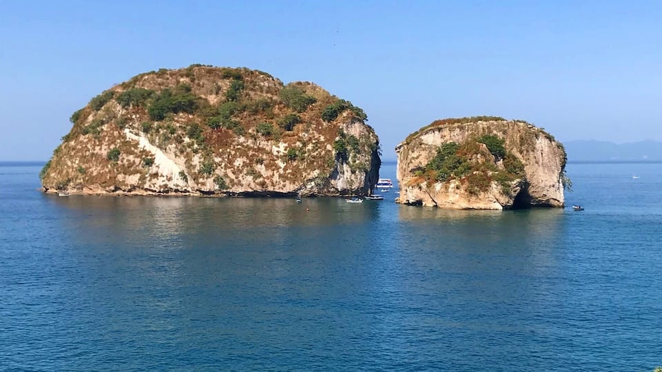A coastal scene with two prominent rocky islands surrounded by clear blue waters.