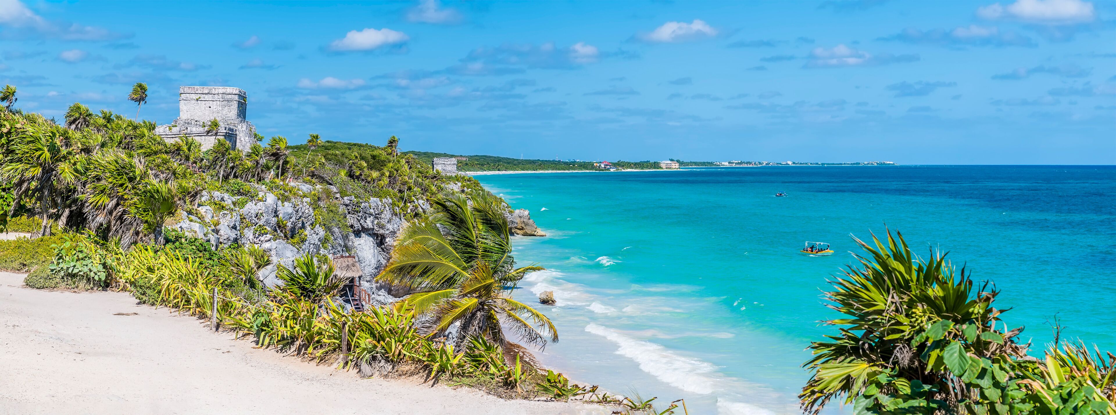 A panorama view from the cliffs along the rocky shoreline at the Mayan settlement of Tulum, Mexico on a sunny day