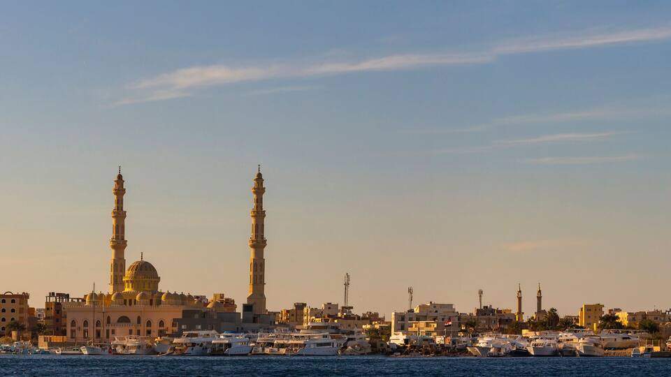 Hurghada, Egypt, a city at sunset. View of the ancient city from the red sea. Panoramic view. A port with ships and a residential area with a mosque.