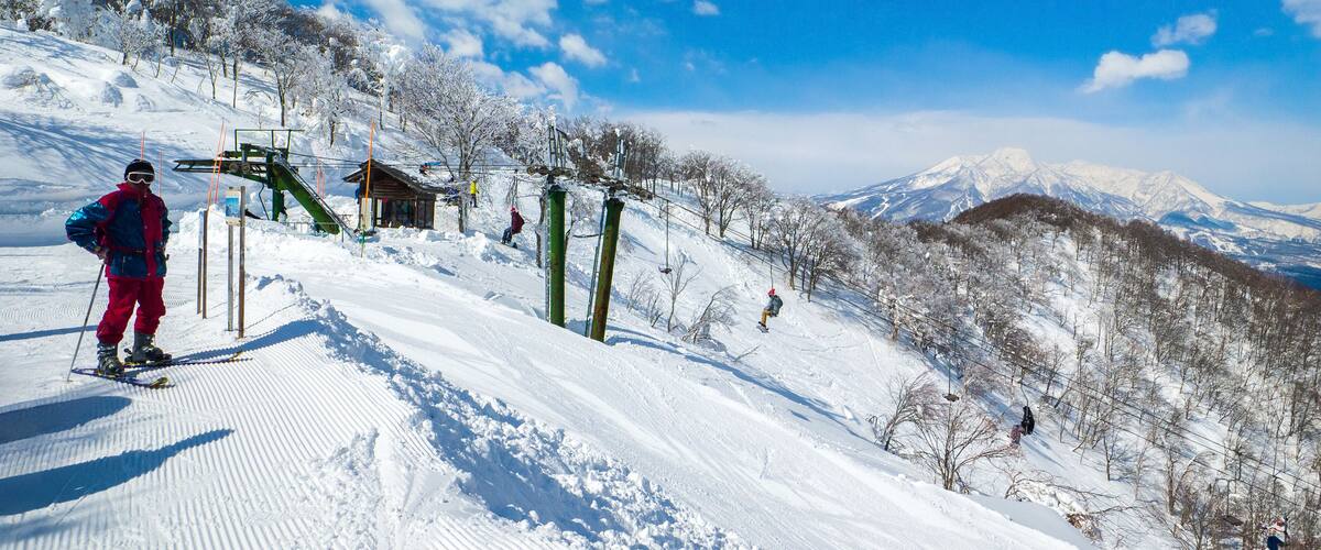 Single chair lifts in a ski resort and snowy peaks in a distant on a sunny day (Madarao Kogen, Nagano, Japan)