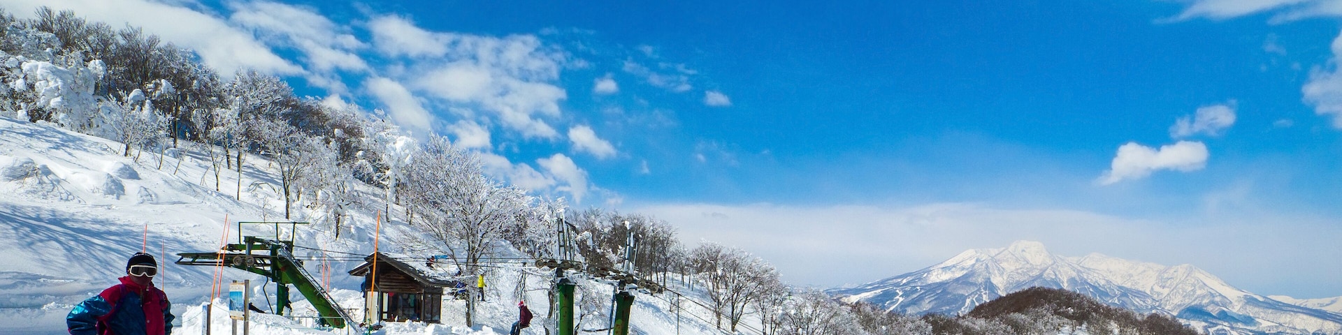 Single chair lifts in a ski resort and snowy peaks in a distant on a sunny day (Madarao Kogen, Nagano, Japan)