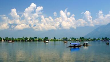 A calm lake with boats, a clear sky, and mountains in the background.