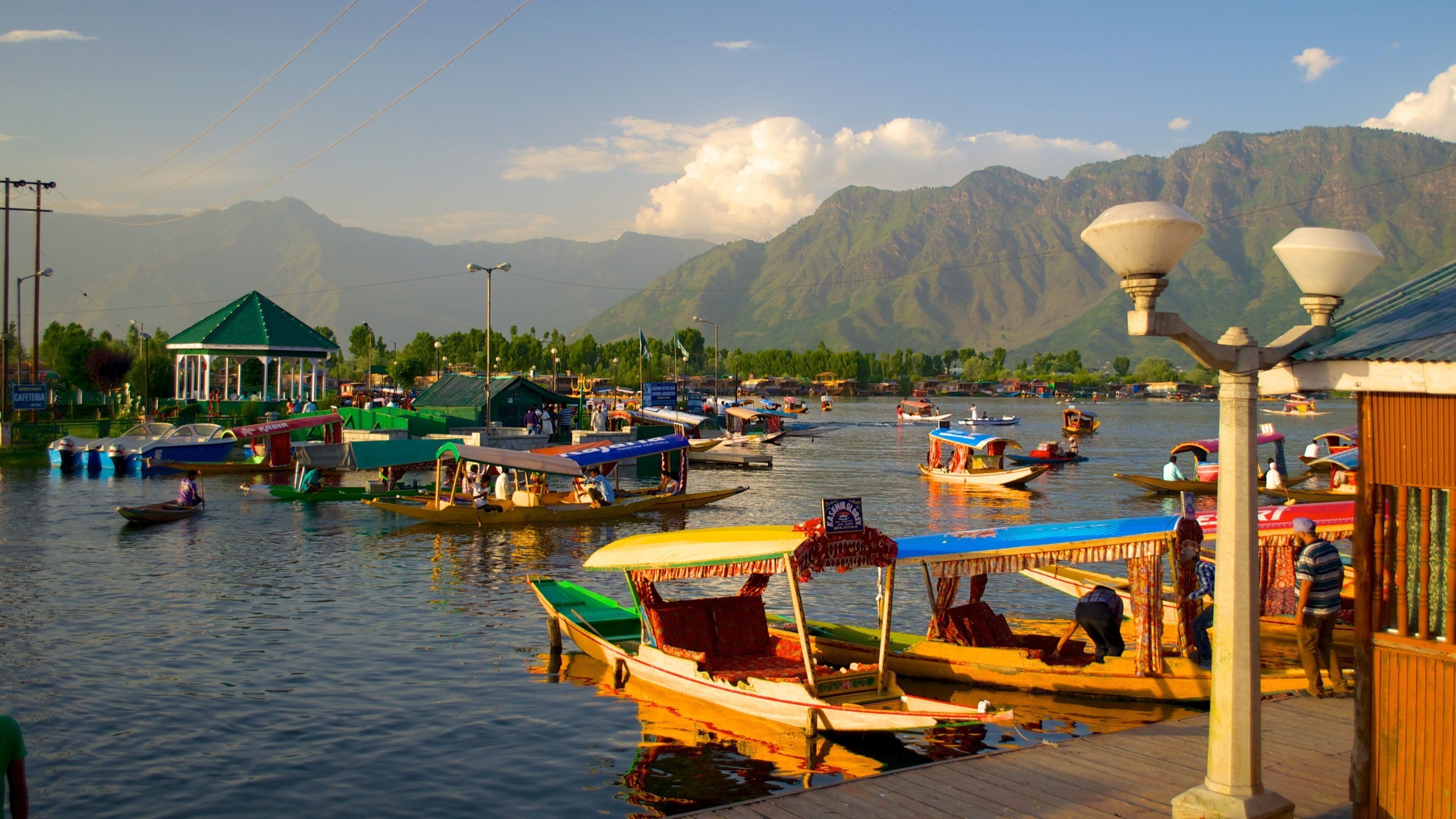 A riverside with boats, a gazebo, and mountains in the background.