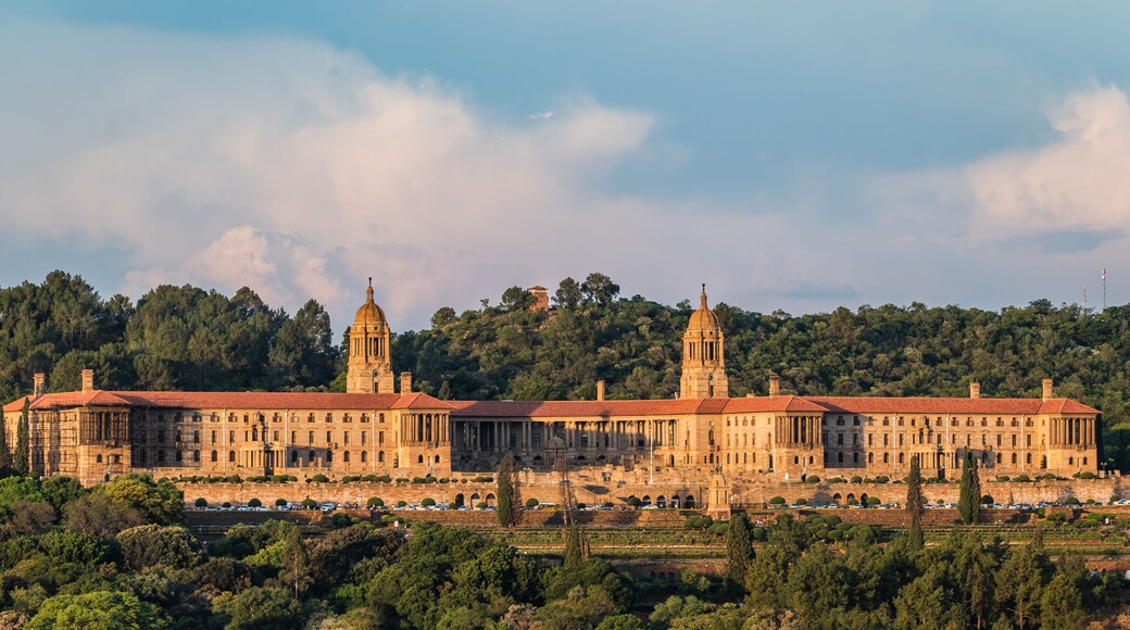 Ein großes, historisches Gebäude mit zwei markanten Türmen, umgeben von üppiger Vegetation und einer hügeligen Landschaft.